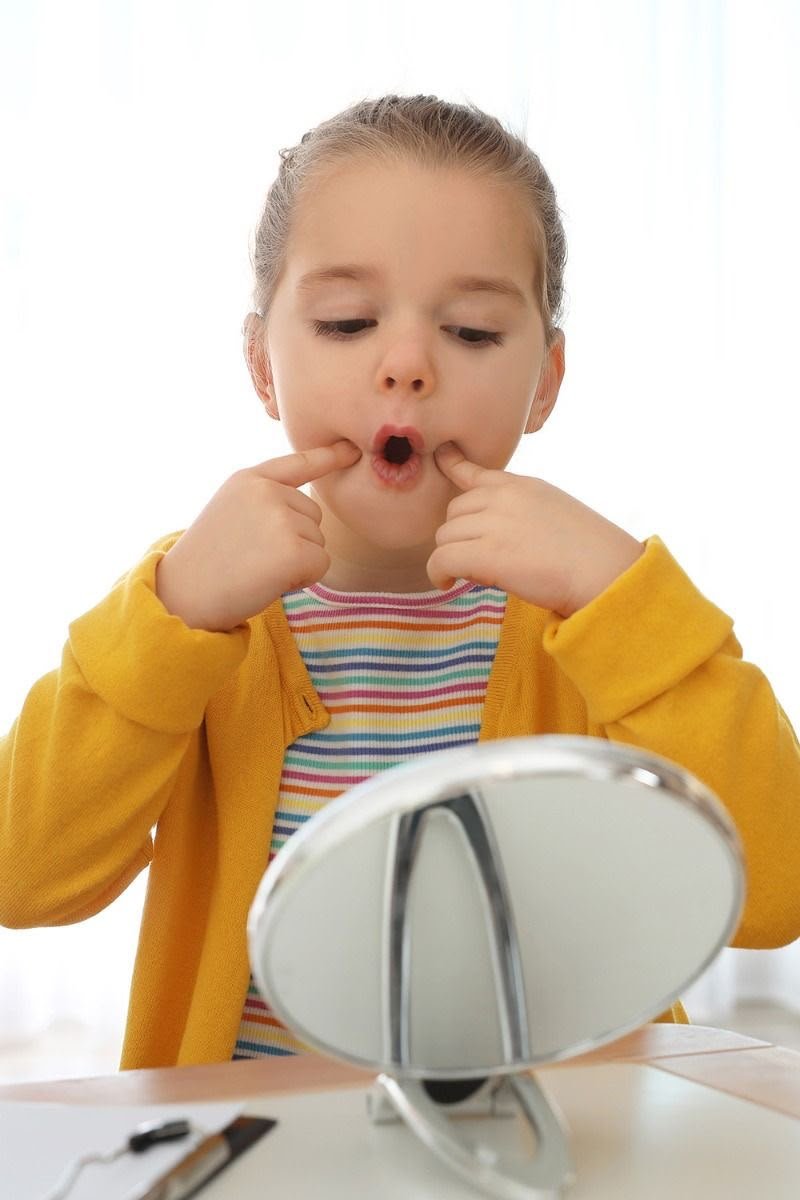 Child practising mouth shapes with a mirror